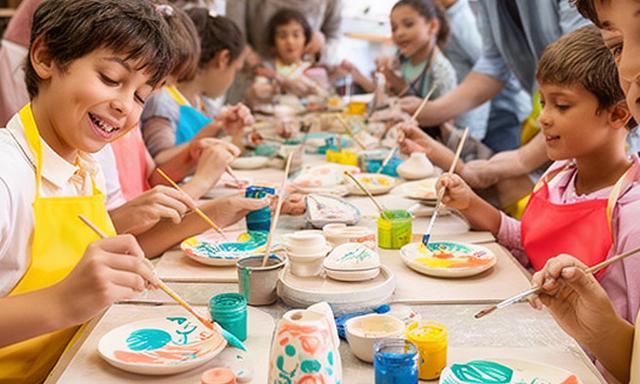 Niños pintando cerámicas en un taller creativo de ocio familiar en Benidorm